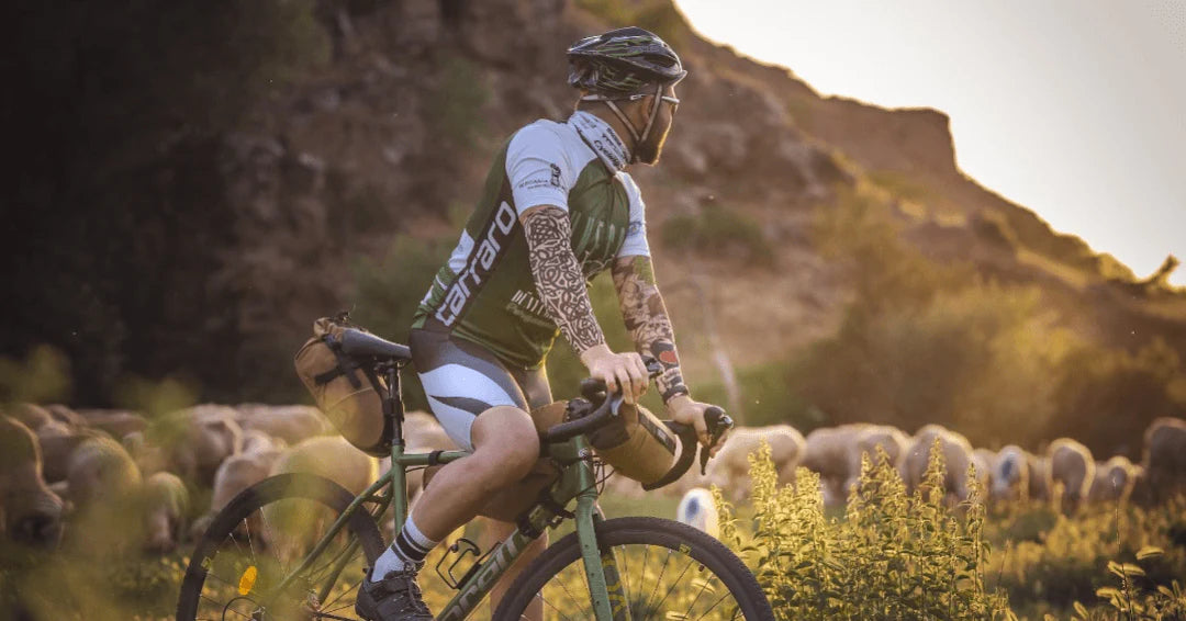 Cycliste sur un vélo Gravel dans la montagne avec des moutons - Loop Sports