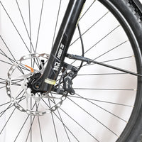 Gros plan sur la roue avant, le frein à disque et la fourche SR Suntour Mobie 25 du vélo Loop Sports Bulls Cross Evo