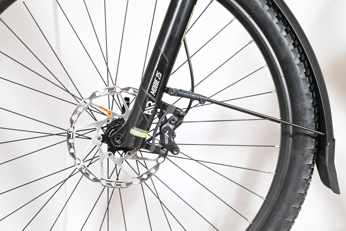 Gros plan sur la roue avant, le frein à disque et la fourche SR Suntour Mobie 25 du vélo Loop Sports Bulls Cross Evo