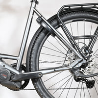 Gros plan sur le cadre gris et la roue arrière du vélo électrique Loop Sports Bulls Cross Evo Lite 1 avec porte-bagages