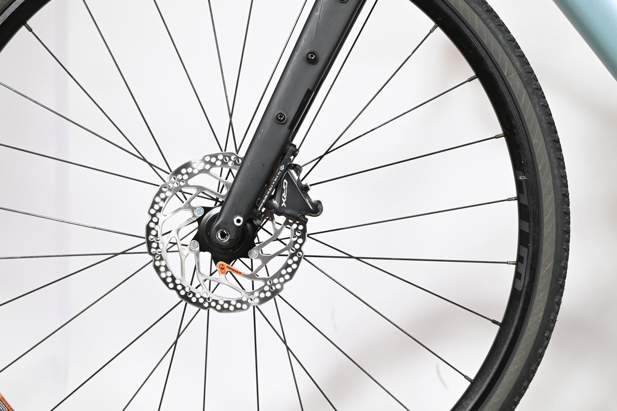 Gros plan sur le frein à disque hydraulique Shimano GRX et la fourche en carbone du vélo Loop Sports Cannondale Topstone