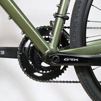 Gros plan sur le pédalier Shimano GRX et le cadre vert olive du vélo gravel Carver Gravel 120 de Loop Sports