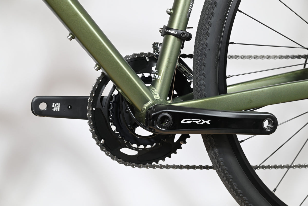 Gros plan sur le pédalier Shimano GRX et le cadre vert olive du vélo gravel Carver Gravel 120 de Loop Sports