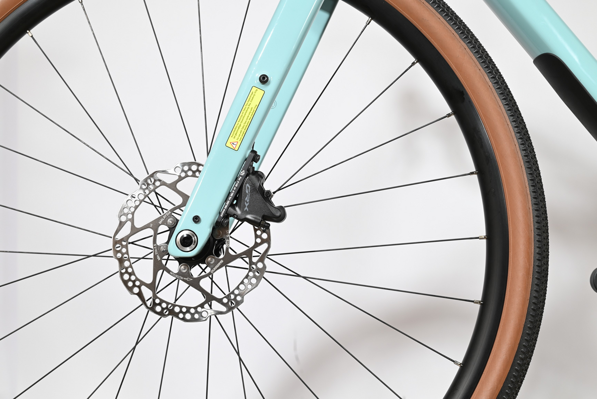 Gros plan sur la fourche bleu clair et le frein à disque Shimano GRX du vélo gravel Loop Sports Cube Nuroad C:62 ONE