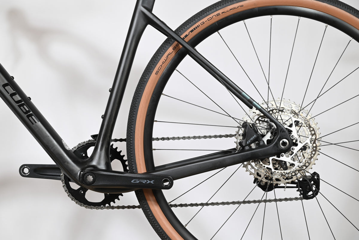 Gros plan sur la transmission et la roue arrière du vélo gravel Loop Sports Cube Nuroad C:62 ONE noir avec pneus tan