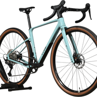 Velo gravel Loop Sports Cube Nuroad C:62 ONE 2025 bleu clair avec pneus a flancs marron sur support en bois