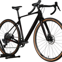 Vélo de gravel Loop Sports Cube Nuroad C:62 SLT noir en carbone avec pneus à flancs beiges sur support en bois