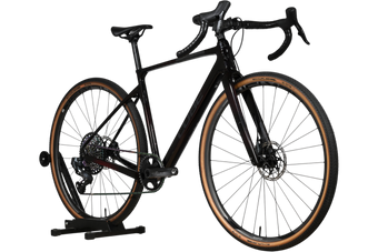 Vélo de gravel Loop Sports Cube Nuroad C:62 SLT noir en carbone avec pneus à flancs beiges sur support en bois
