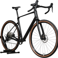 Vélo de gravel Loop Sports Cube Nuroad C:62 ONE 2025 noir mat avec pneus à flancs marron sur support en bois