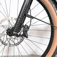 Gros plan sur la fourche RockShox, le disque de frein et le pneu à flanc beige du vélo Loop Sports Cube Reaction Hybrid