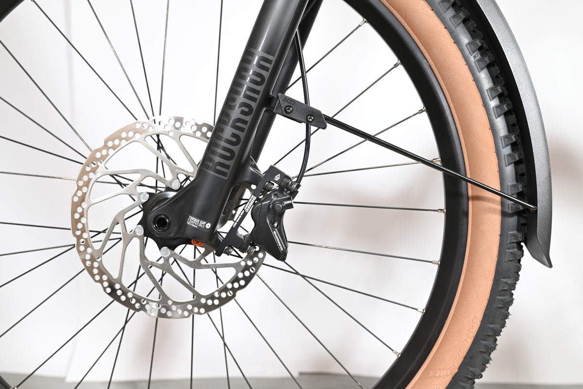 Gros plan sur la fourche RockShox, le disque de frein et le pneu à flanc beige du vélo Loop Sports Cube Reaction Hybrid