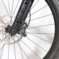 Gros plan sur le frein à disque hydraulique Shimano XT et la fourche noire du vélo électrique Loop Sports Cube Stereo
