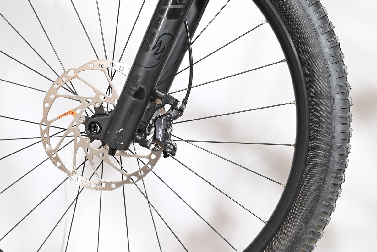 Gros plan sur le frein à disque hydraulique Shimano XT et la fourche noire du vélo électrique Loop Sports Cube Stereo