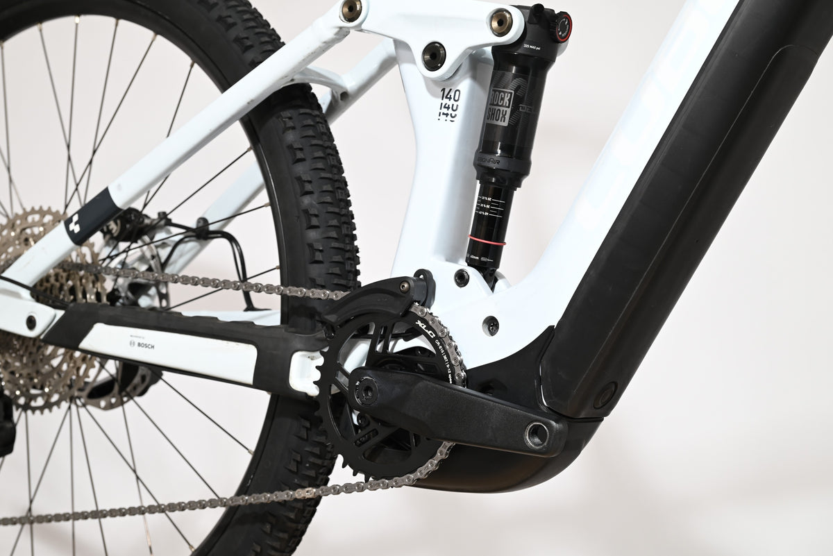 Gros plan sur le cadre blanc et l'amortisseur arrière RockShox du vélo électrique Loop Sports Cube Stereo Hybrid 140