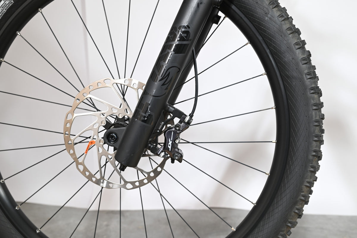 Gros plan sur la roue avant, la fourche noire et le frein à disque hydraulique du vélo Loop Sports Cube Stereo Hybrid