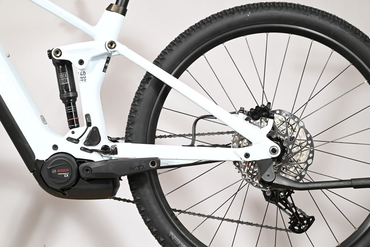 Vue rapprochée du cadre blanc et de la suspension arrière du vélo électrique Loop Sports Cube Stereo Hybrid 140