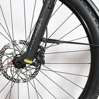 Gros plan sur la roue avant, le frein à disque et la fourche du vélo électrique Loop Sports Focus Aventura 6.7