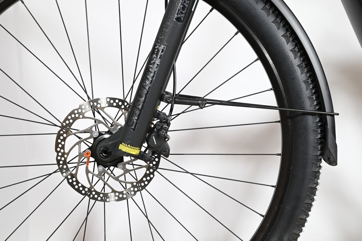 Gros plan sur la roue avant, le frein à disque et la fourche du vélo électrique Loop Sports Focus Aventura 6.7