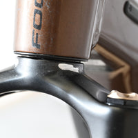 Gros plan sur la fourche noire et le cadre marron d'un vélo électrique Loop Sports Focus Thron 6.8 EQP avec éraflure