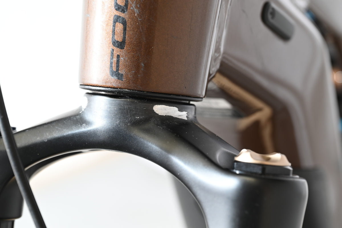 Gros plan sur la fourche noire et le cadre marron d'un vélo électrique Loop Sports Focus Thron 6.8 EQP avec éraflure