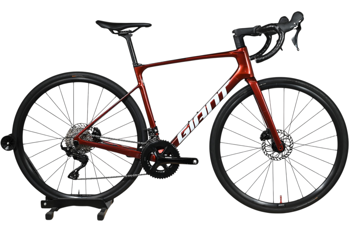 Vélo de route Giant Defy Advanced 2 2025 rouge métallique chez Loop Sports sur un présentoir en bois