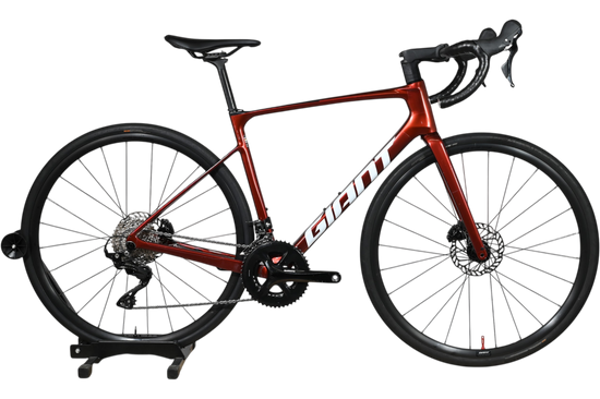 Vélo de route Giant Defy Advanced 2 2025 rouge métallique chez Loop Sports sur un présentoir en bois