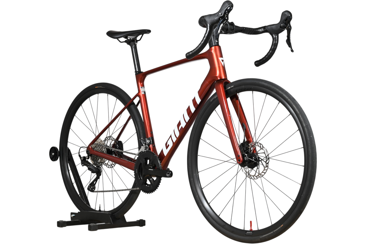 Vélo de route Giant Defy Advanced 2 2025 rouge métallique chez Loop Sports sur support en bois