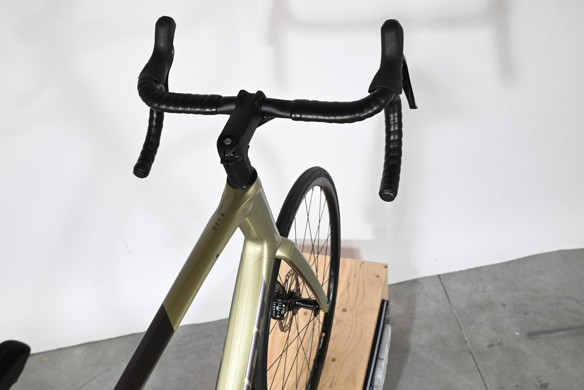 Vue plongeante sur le guidon et le cadre vert olive du vélo de route Giant Defy Advanced 2 2024 chez Loop Sports