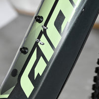 Gros plan sur le cadre noir et vert du vélo électrique Giant Fathom E+1 de Loop Sports avec des éraflures visibles.