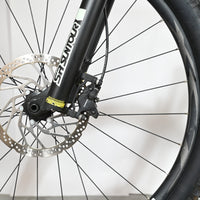 Gros plan sur la roue avant, le frein à disque et la fourche SR Suntour du vélo électrique Giant Fathom E+1 Loop Sports