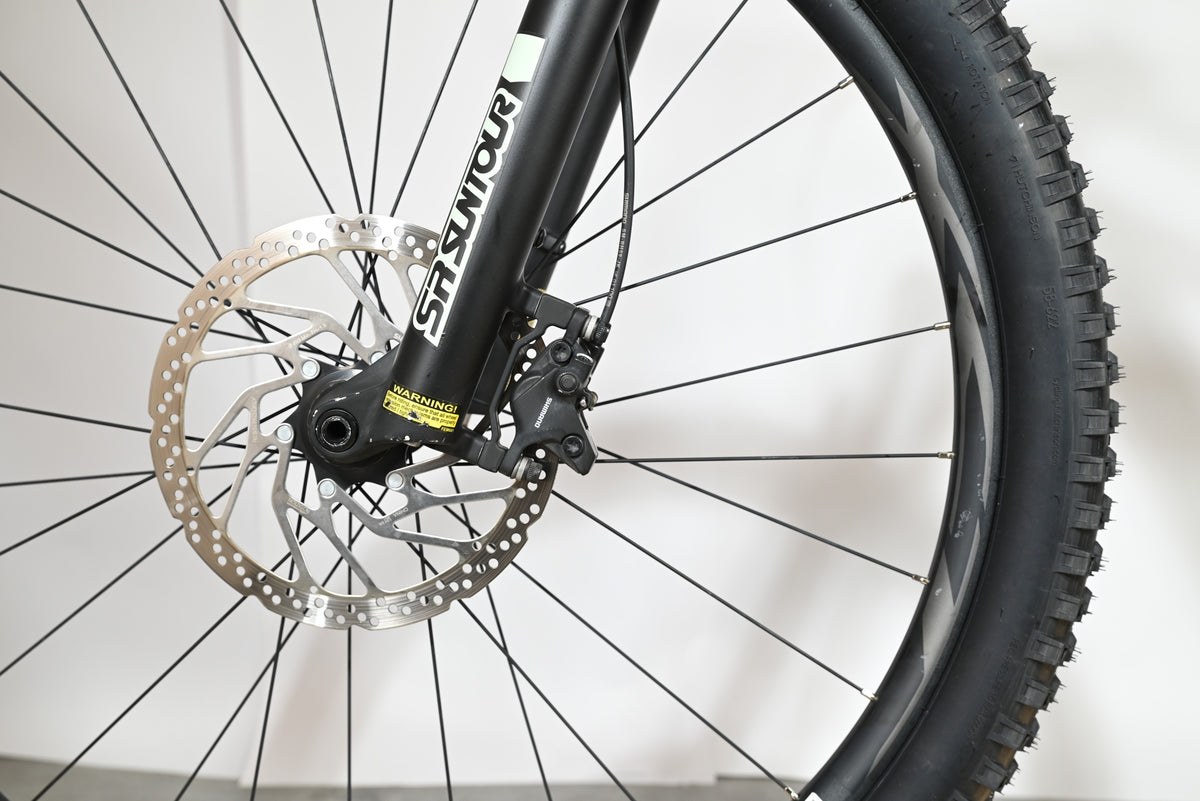 Gros plan sur la roue avant, le frein à disque et la fourche SR Suntour du vélo électrique Giant Fathom E+1 Loop Sports