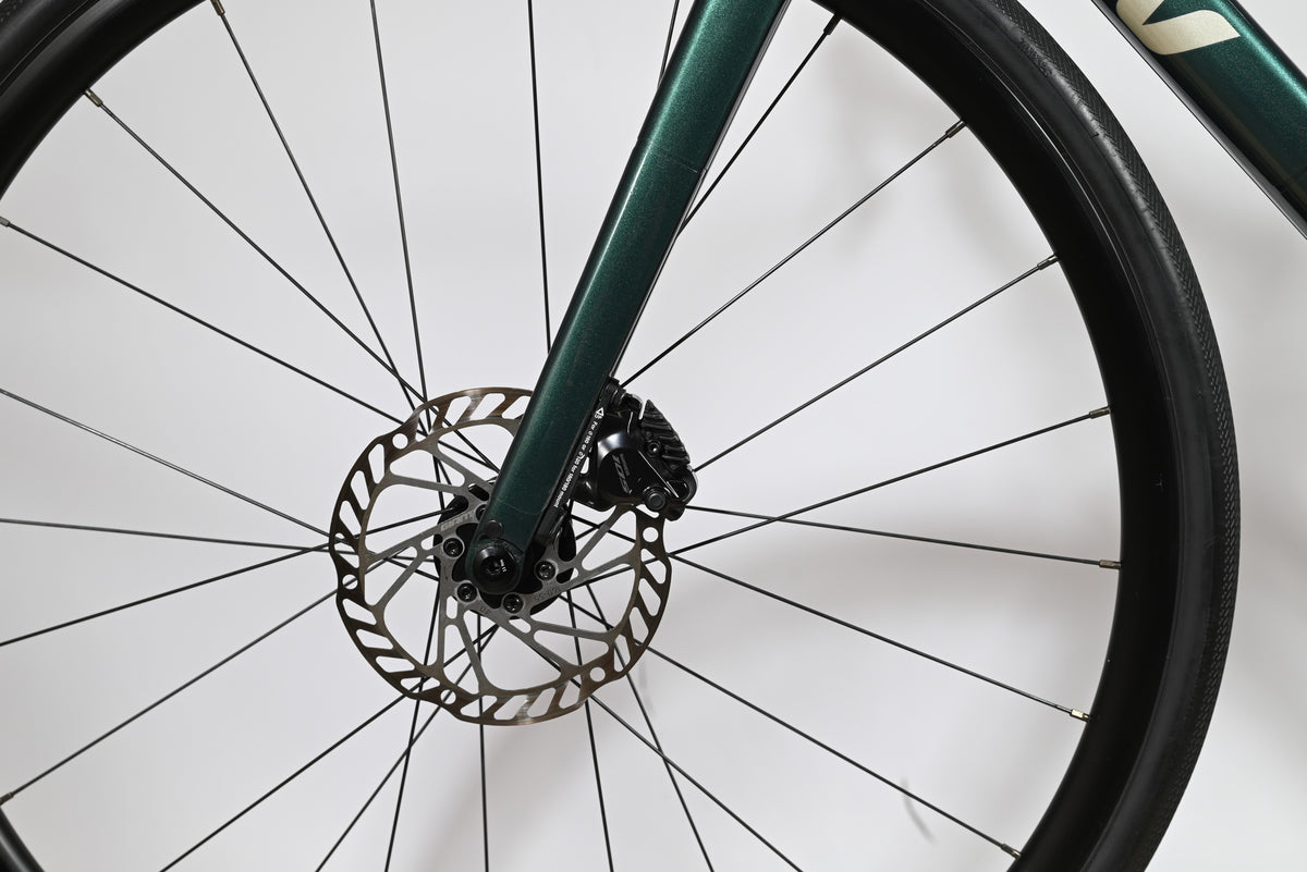Gros plan sur la fourche vert foncé et le frein à disque hydraulique du vélo de route Loop Sports Giant Liv Avail