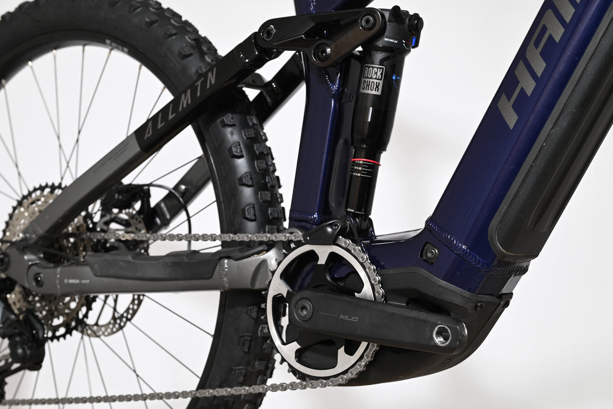 Gros plan sur le cadre bleu et l'amortisseur arrière RockShox du vélo électrique Haibike Allmtn 6 de Loop Sports