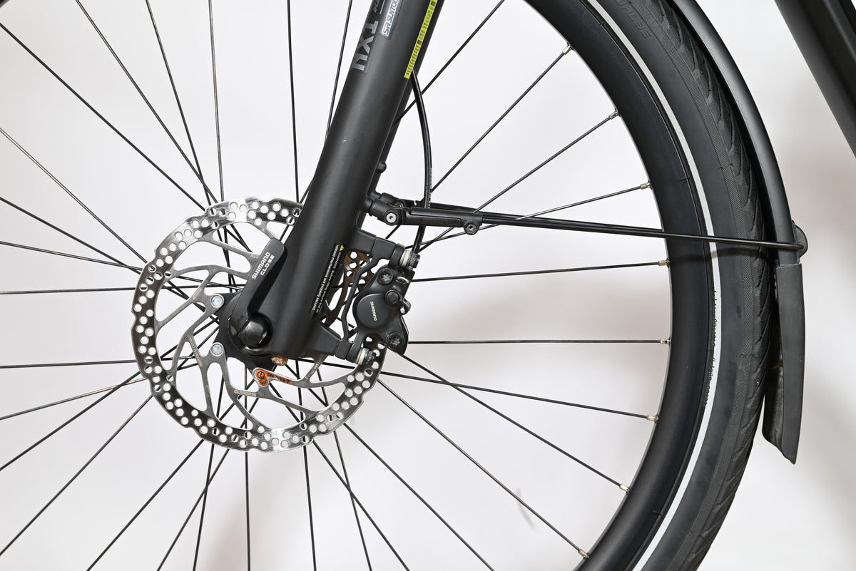 Gros plan sur le frein à disque hydraulique Shimano et la fourche avant du vélo électrique Loop Sports KTM Macina Tour