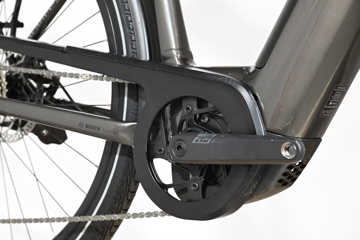 Gros plan sur le pédalier et le moteur Bosch d'un vélo électrique Loop Sports KTM Macina Style XL gris