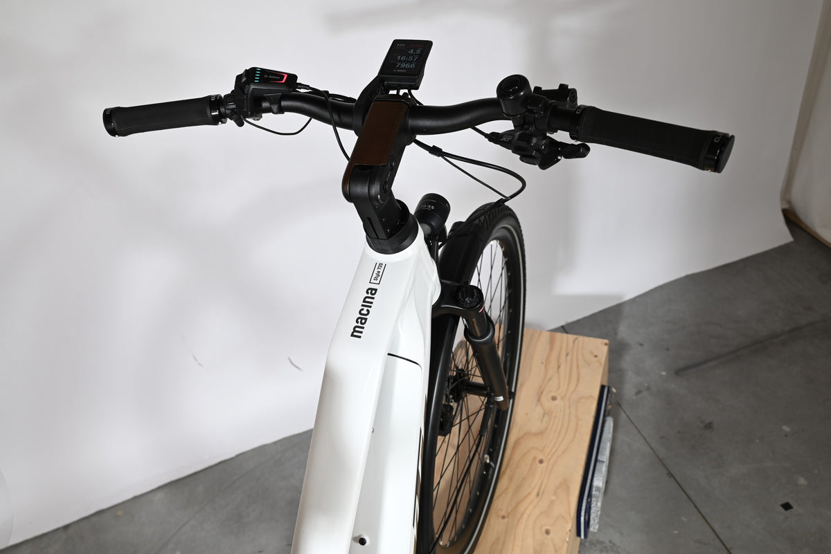 Vue plongeante sur le guidon et le cadre blanc du vélo électrique Loop Sports KTM Macina Style 720 avec écran Bosch