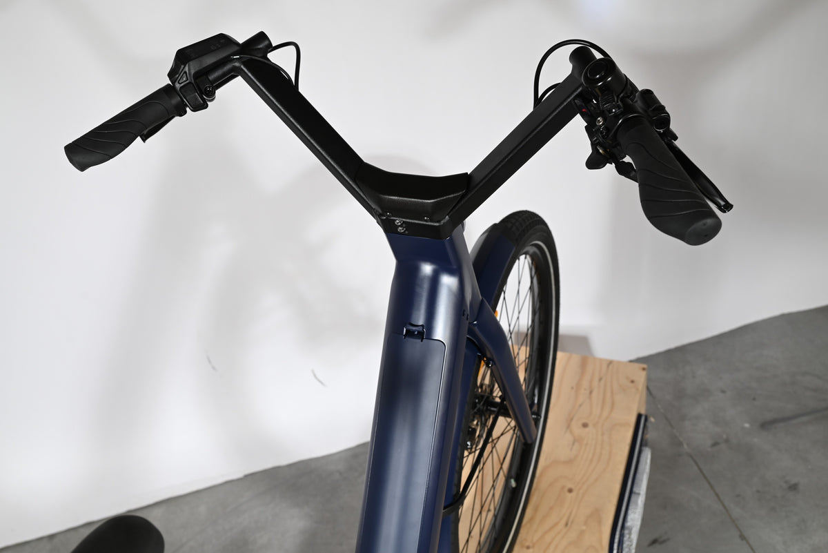 Vue plongeante sur le guidon et le cadre bleu marine du vélo électrique Moustache Lundi 27.6 chez Loop Sports