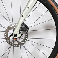 Gros plan sur le frein à disque hydraulique Shimano GRX et la fourche beige du vélo gravel Pinarello Grevil F1 Loop Sports