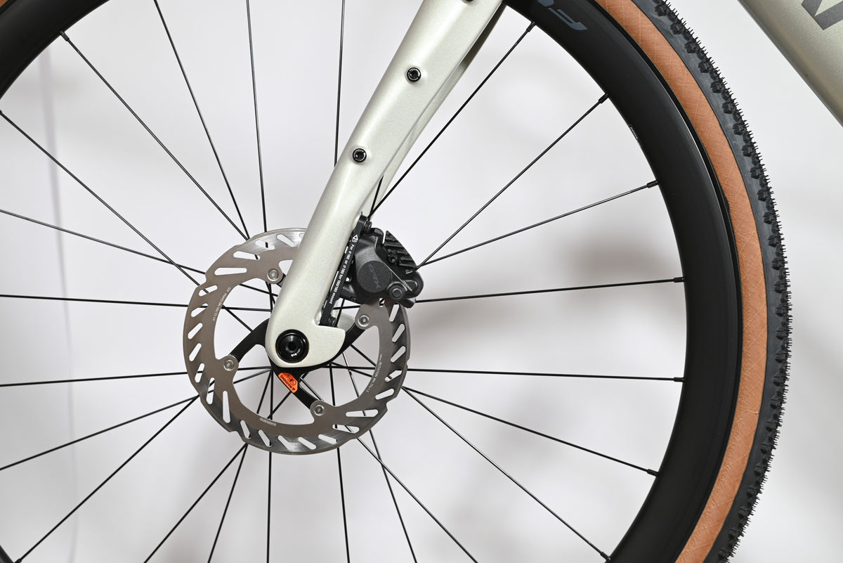 Gros plan sur le frein à disque hydraulique Shimano GRX et la fourche beige du vélo gravel Pinarello Grevil F1 Loop Sports