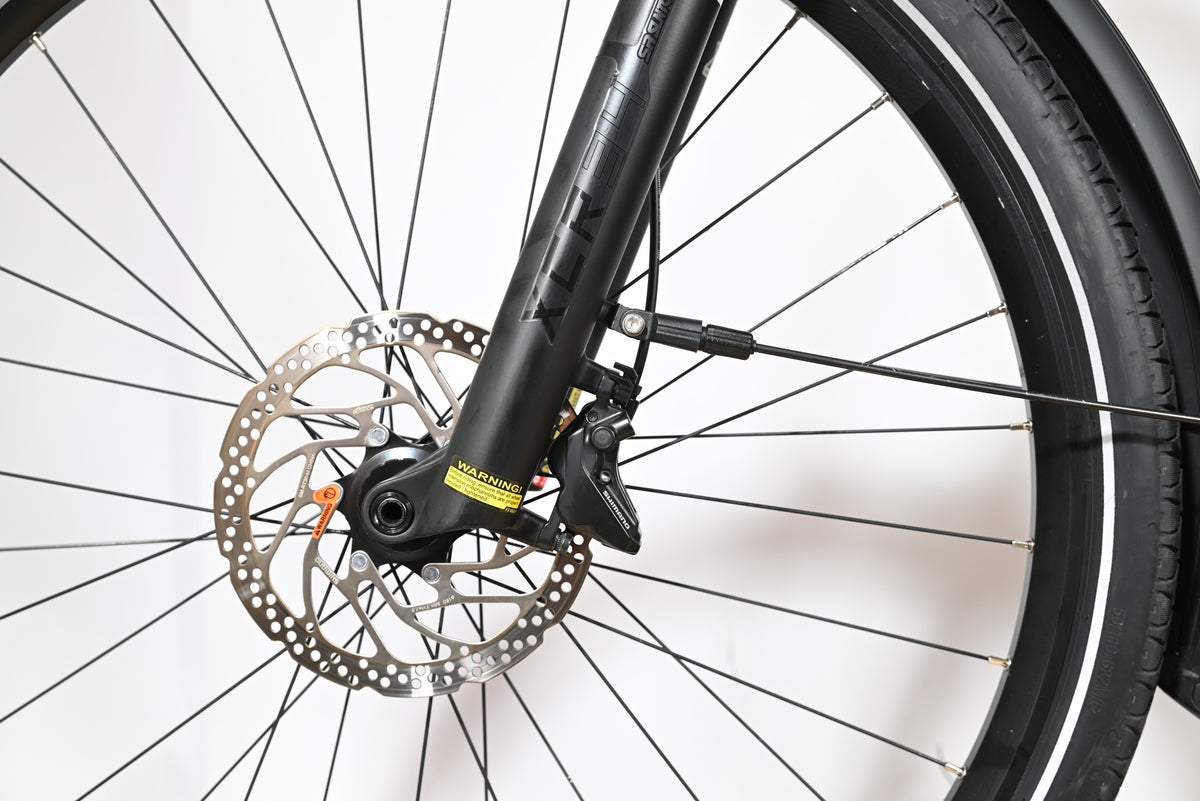 Gros plan sur la roue avant et la fourche à suspension noire du vélo Loop Sports Scott Axis 10 avec frein à disque