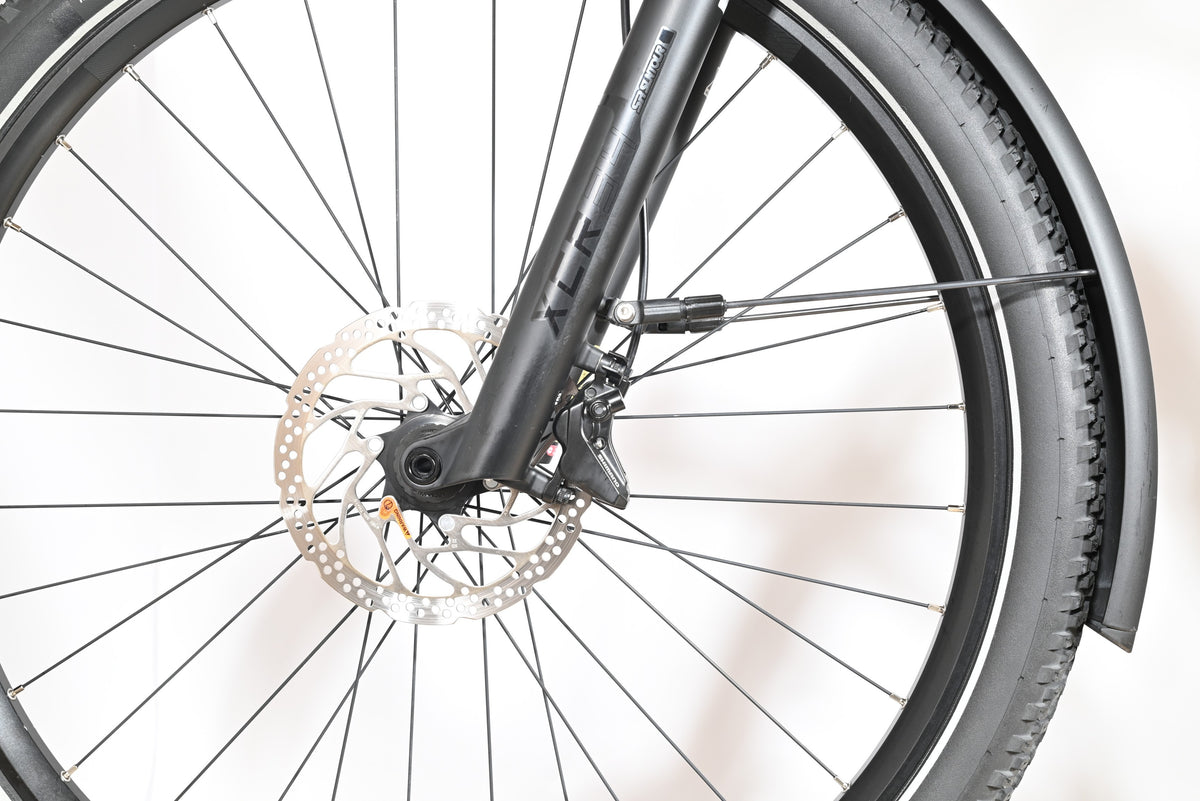 Gros plan sur la roue avant et la fourche suspendue Suntour du vélo électrique Loop Sports Scott Axis 10 noir