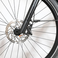 Gros plan sur la roue avant, le frein à disque et la fourche noire du vélo Scott Axis 10 chez Loop Sports