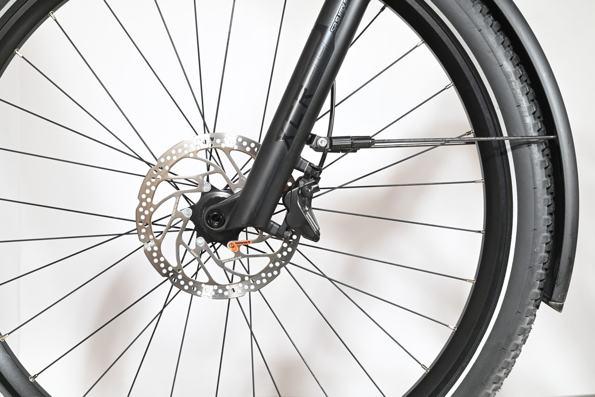 Gros plan sur la roue avant, le frein à disque et la fourche noire du vélo Scott Axis 10 chez Loop Sports