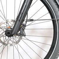Gros plan sur la roue avant et le frein à disque du vélo Scott Axis 10 de Loop Sports avec garde-boue noir