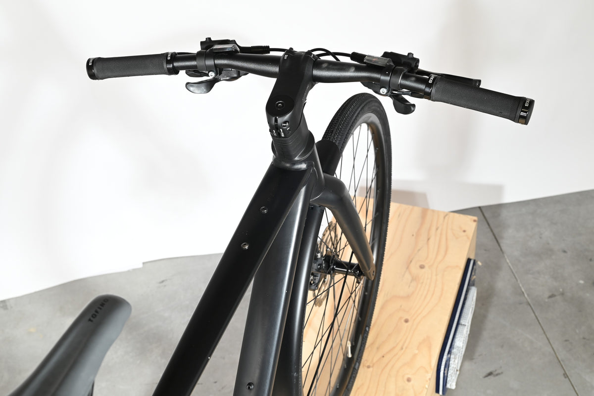 Vue plongeante sur le guidon et le cadre noir mat du vélo hybride Scott Metrix 30 EQ 2024 chez Loop Sports