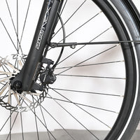 Gros plan sur la roue avant, le frein à disque Tektro et la fourche SR Suntour du vélo électrique Loop Sports Tenways