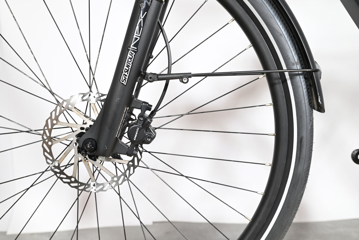 Gros plan sur la roue avant, le frein à disque Tektro et la fourche SR Suntour du vélo électrique Loop Sports Tenways