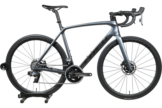 Vélo de route Trek Emonda SL7 AXS 2023 gris carbone chez Loop Sports sur un support en bois