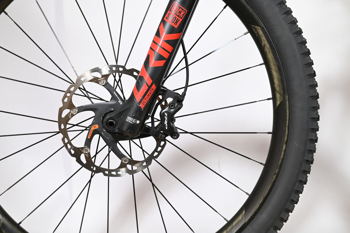 Gros plan sur la roue avant et la fourche RockShox noire et rouge du vélo électrique Trek Rail 9.9 chez Loop Sports