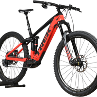 VTT électrique Trek Rail 9.9 2024 rouge et noir de Loop Sports, cadre taille L, vue de profil sur support en bois
